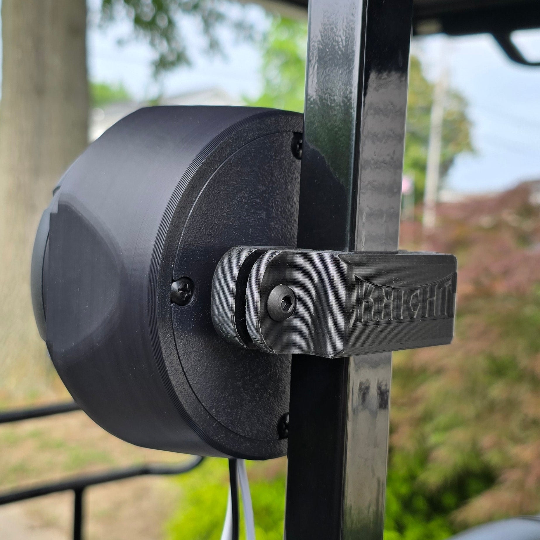 Close-up of a speaker mount on a vehicle with a blurred outdoor background