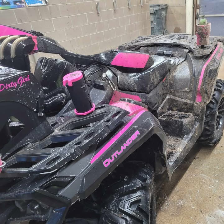 Black and pink ATV parked indoors with a concrete floor and wall in the background.