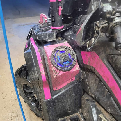 Close-up of a vehicle with pink speaker pods on a black vehicle with pink decals